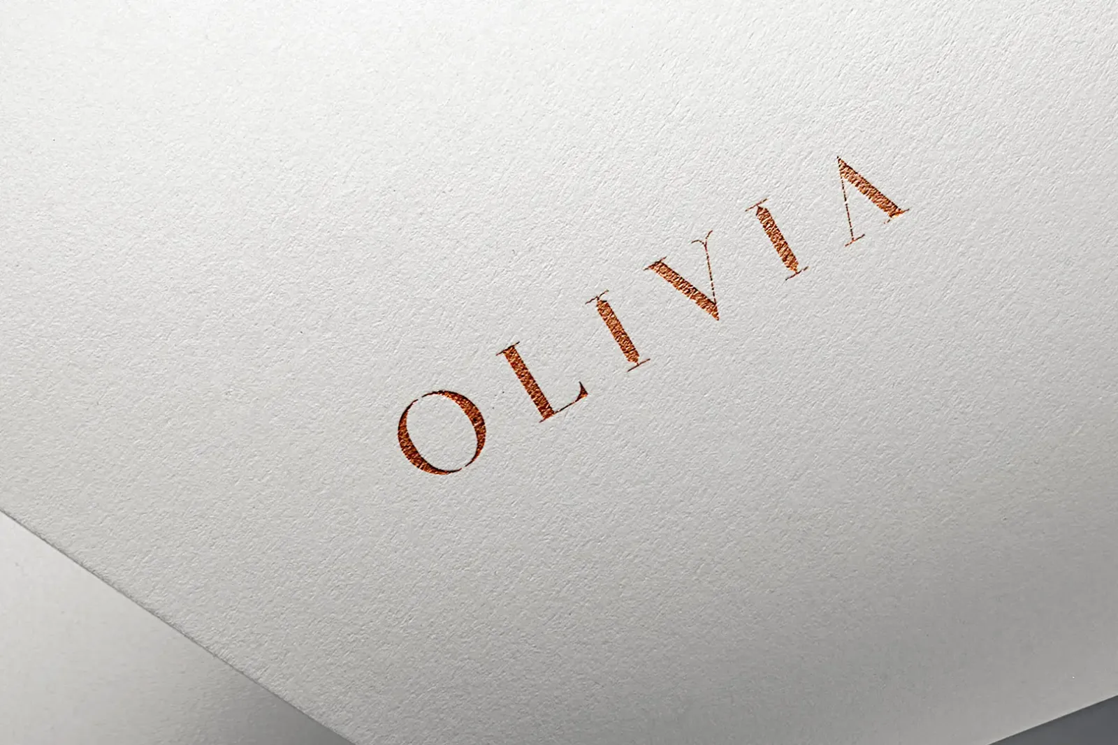 Olivia Boutique custom serif wordmark foil-stamped in copper on white cotton paper with generous letter spacing and refined geometric letterforms