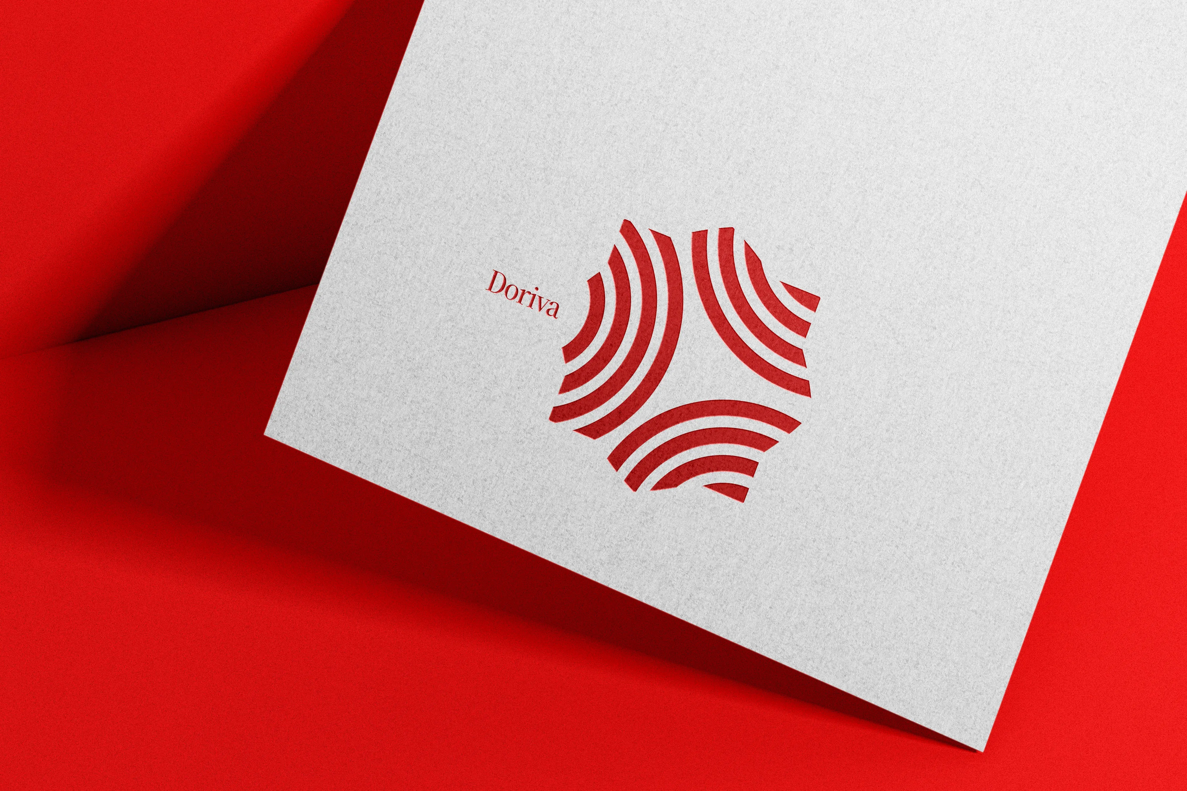 Doriva logo in red variant on white paper angled on red background showing the ripple mark and wordmark in a presentation context